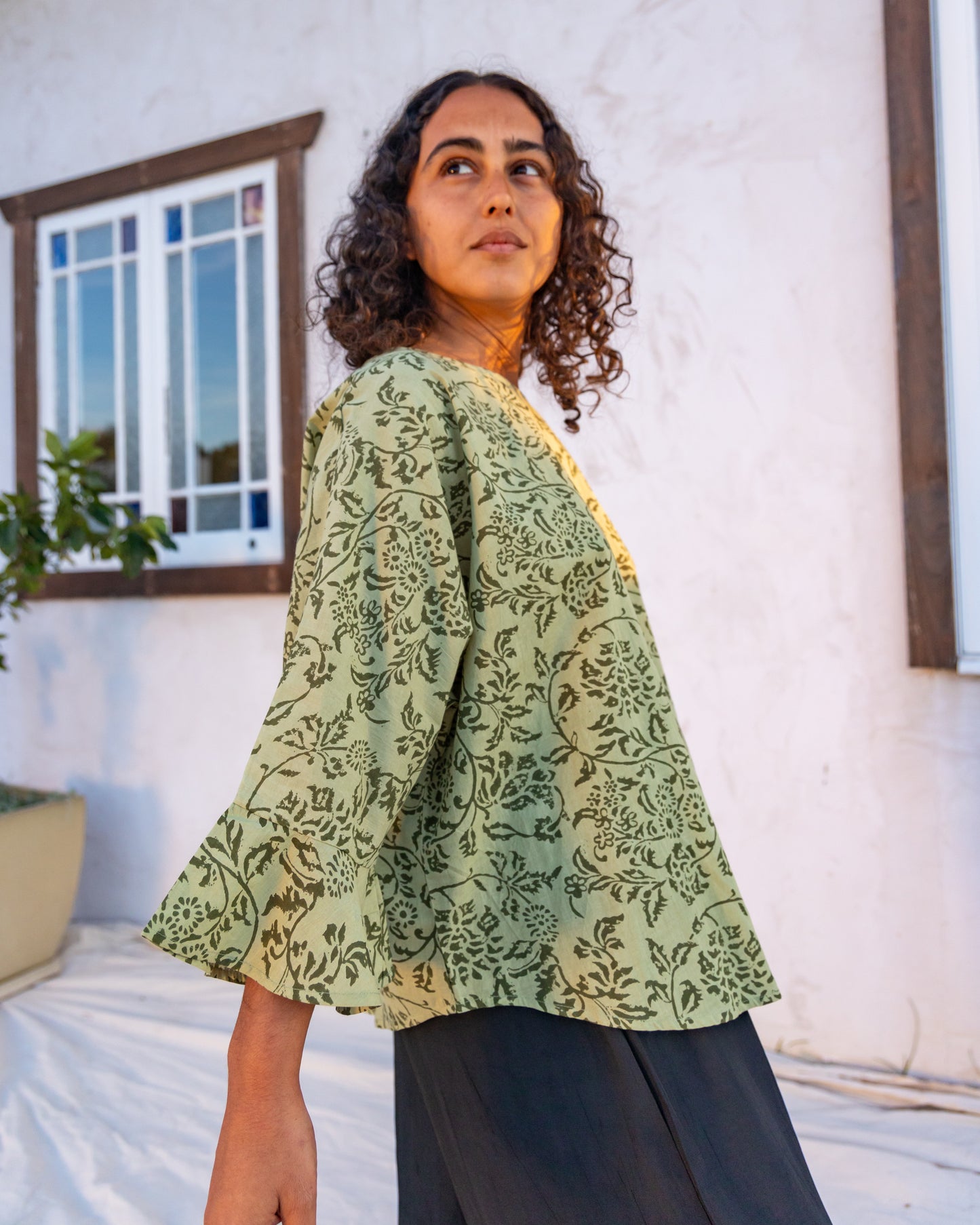 
                  
                    woman dressed in boa flared top in gooseberry print standing in front of a white wall
                  
                