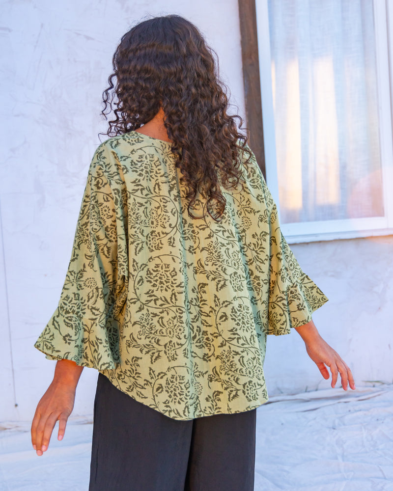 
                  
                    woman dressed in boa flared top in gooseberry print standing in front of a white wall
                  
                