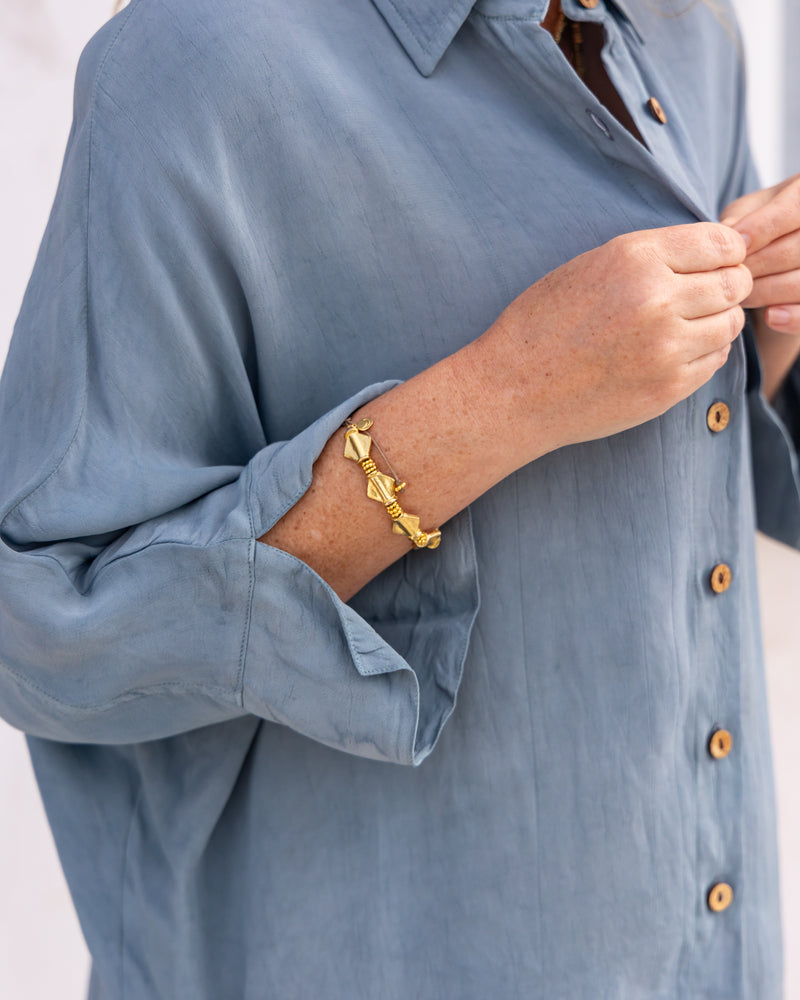 
                  
                    woman dressed in bouviet oversized shirt and miguel straight legged pants in orange peel fibre in cornflower blue standing in front of a white wall
                  
                