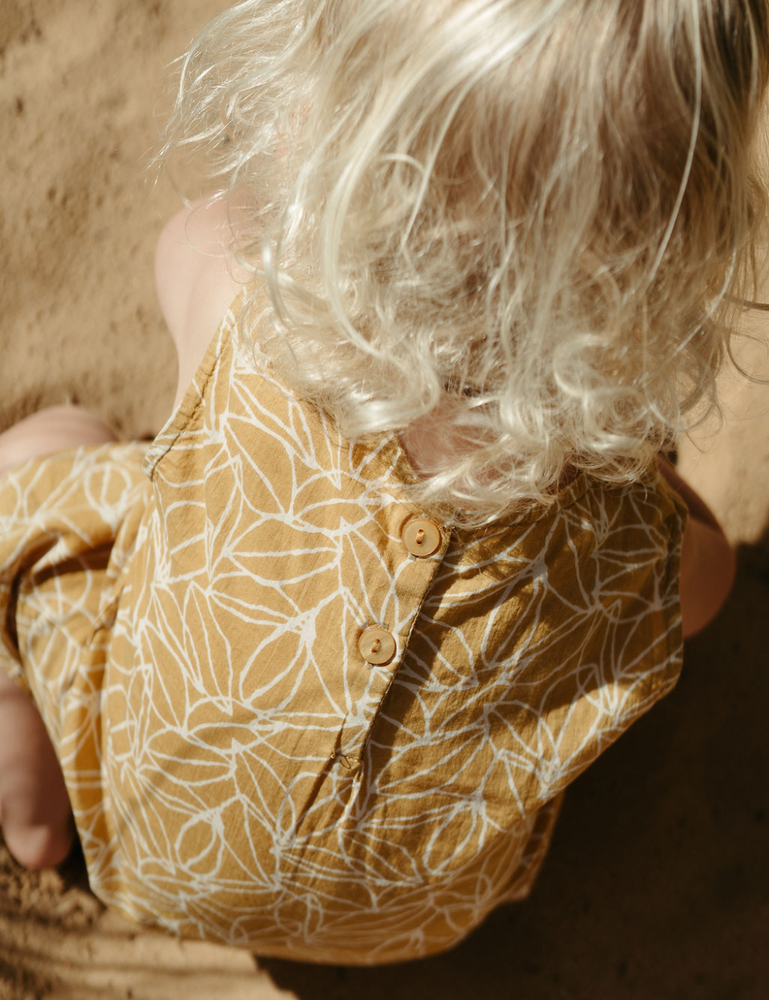 
                  
                    Young girl on beach playing from the back in fogo straight dress in mustard seed print
                  
                