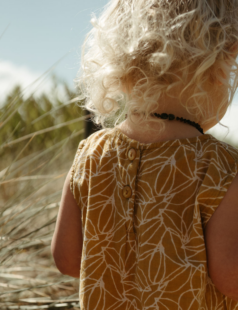 
                  
                    Young girl from the back on beach in fogo straight dress in mustard seed print
                  
                