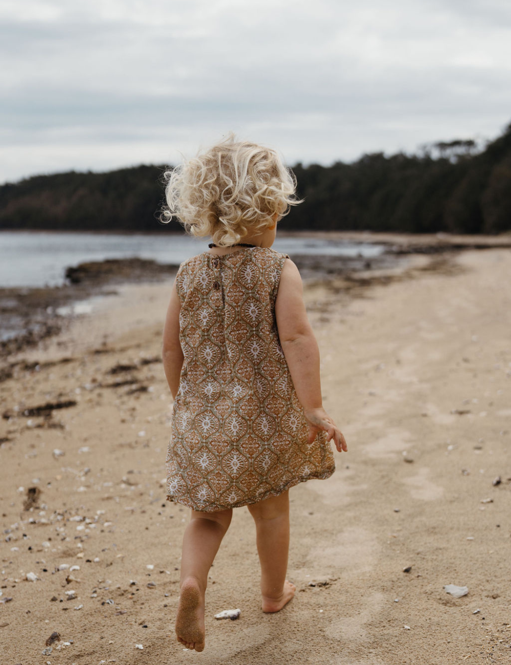 
                  
                    Young girl running on beach in fogo straight dress in retro funk print
                  
                