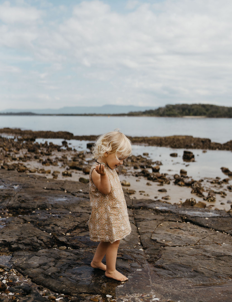 
                  
                    girl walking on rocks at beach in fogo straight dress in retro funk print
                  
                