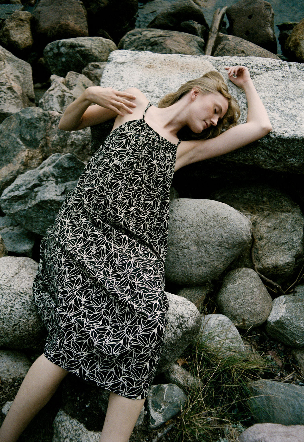 woman dressed in black and white patterned midi dress in front of rocks