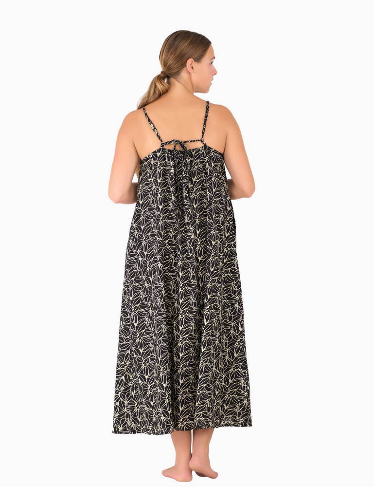 
                  
                    woman dressed in dark patterned gomera maxi dress in dark plum print in front of white background from back
                  
                