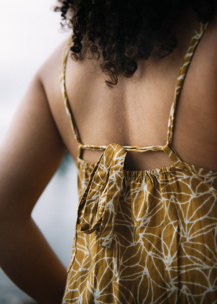 back of woman dressed in mustard and white patterned midi dress