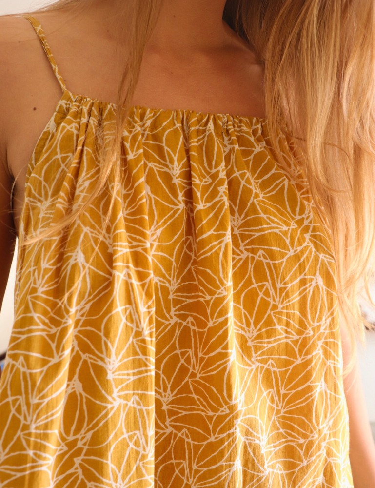 
                  
                    woman dressed in light patterned gomera maxi dress in mustard seed print
                  
                