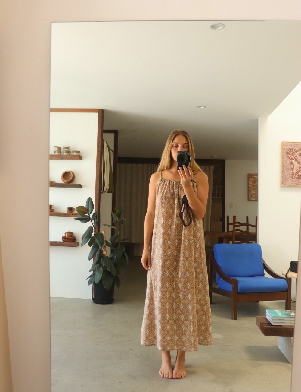 woman dressed in light patterned maxi dress in retro funk print in front of mirror in Byron Bay