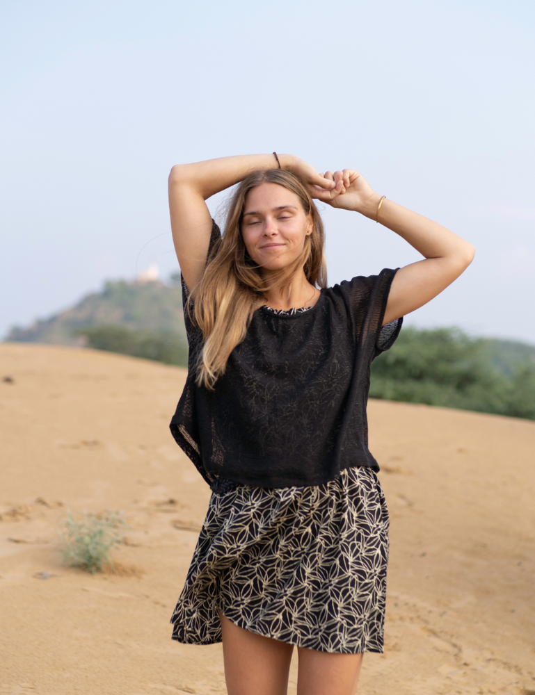 woman dressed in dark patterned mini dress with oversized net charcoal top in Indian desert