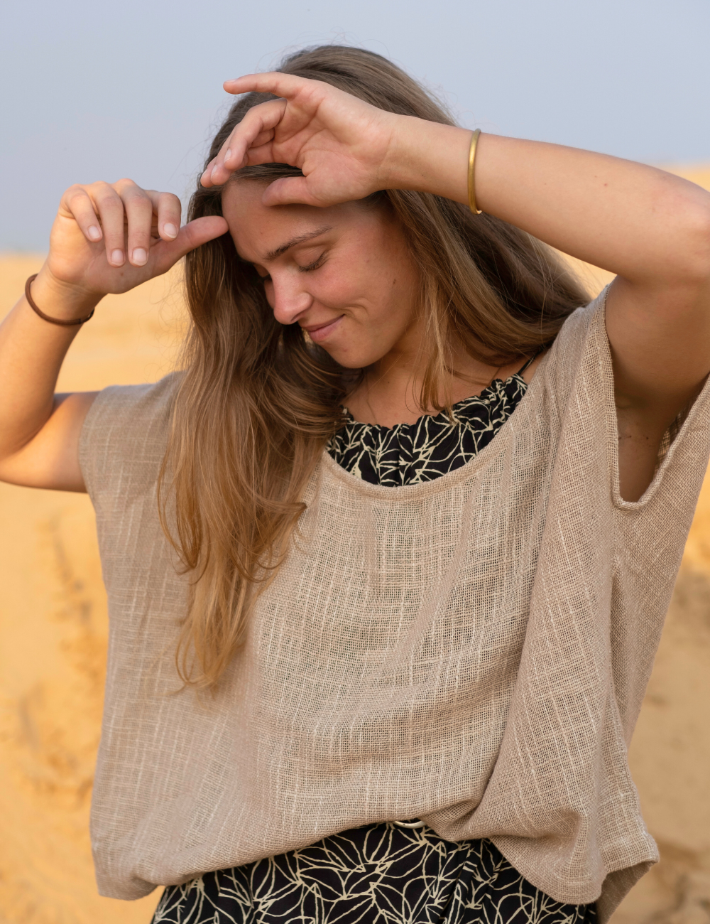 woman dressed in dark patterned mini dress with oversized taupe coloured top in Indian desert