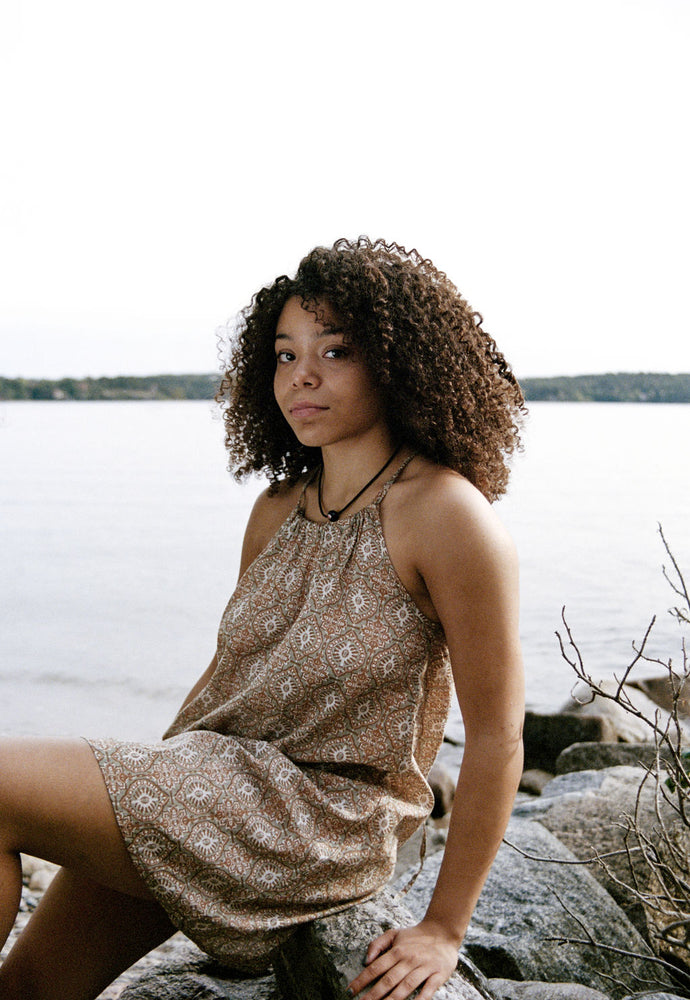 
                  
                    women dressed in beige patterned mini dress in front of ocean
                  
                