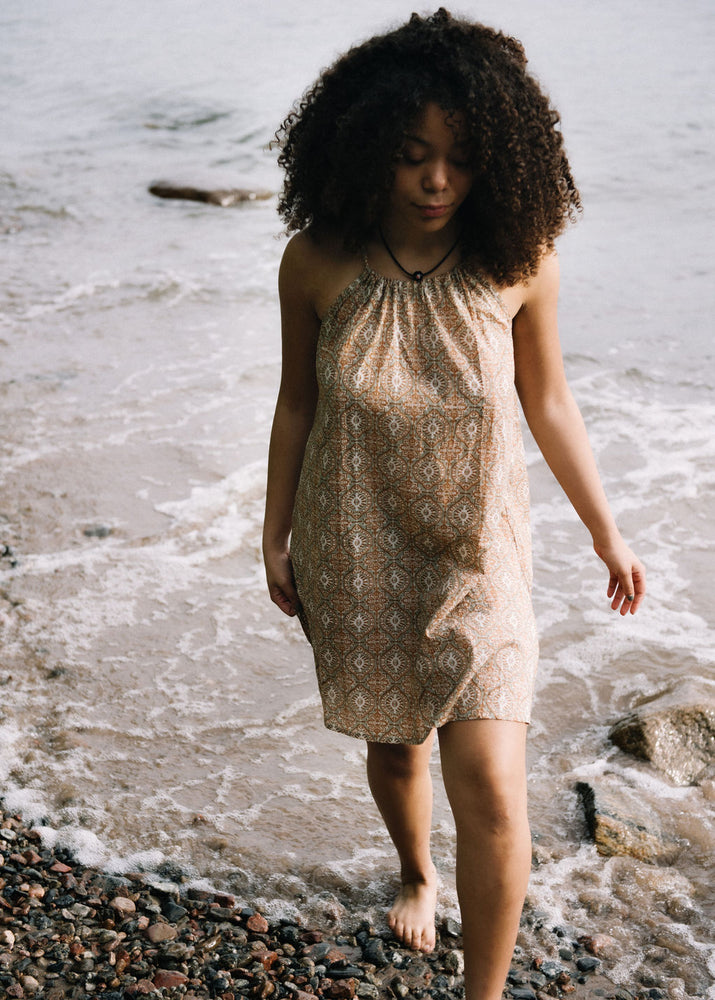 women dressed in beige patterned mini dress in front of ocean