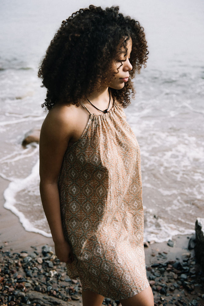
                  
                    women dressed in beige patterned mini dress in front of ocean
                  
                