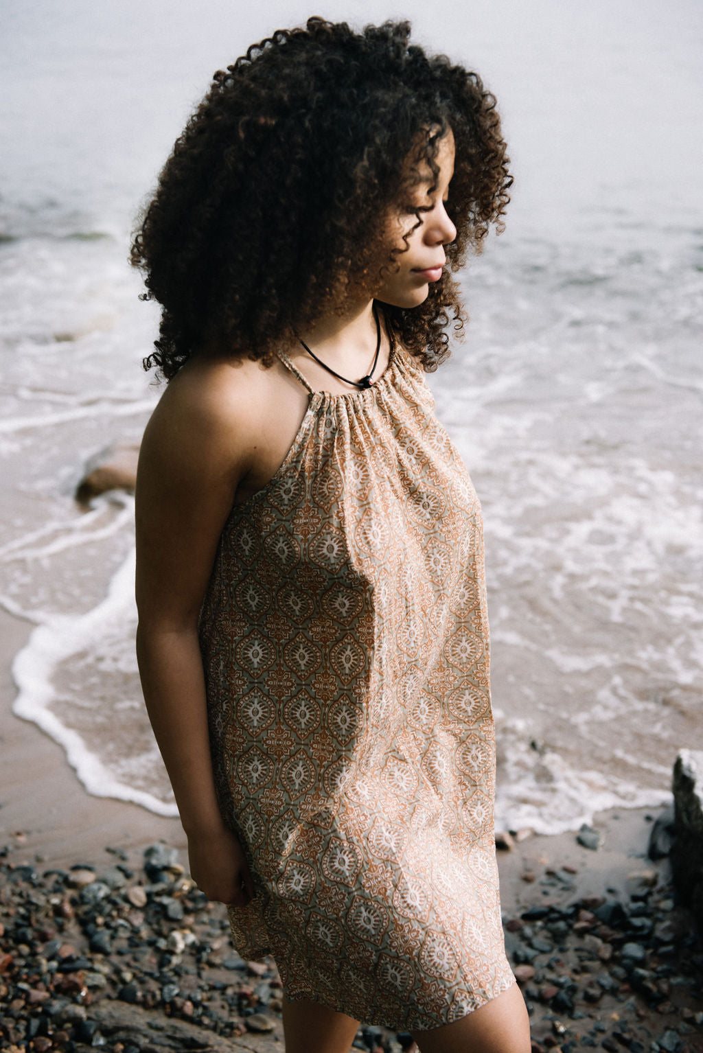 
                  
                    women dressed in beige patterned mini dress in front of ocean
                  
                