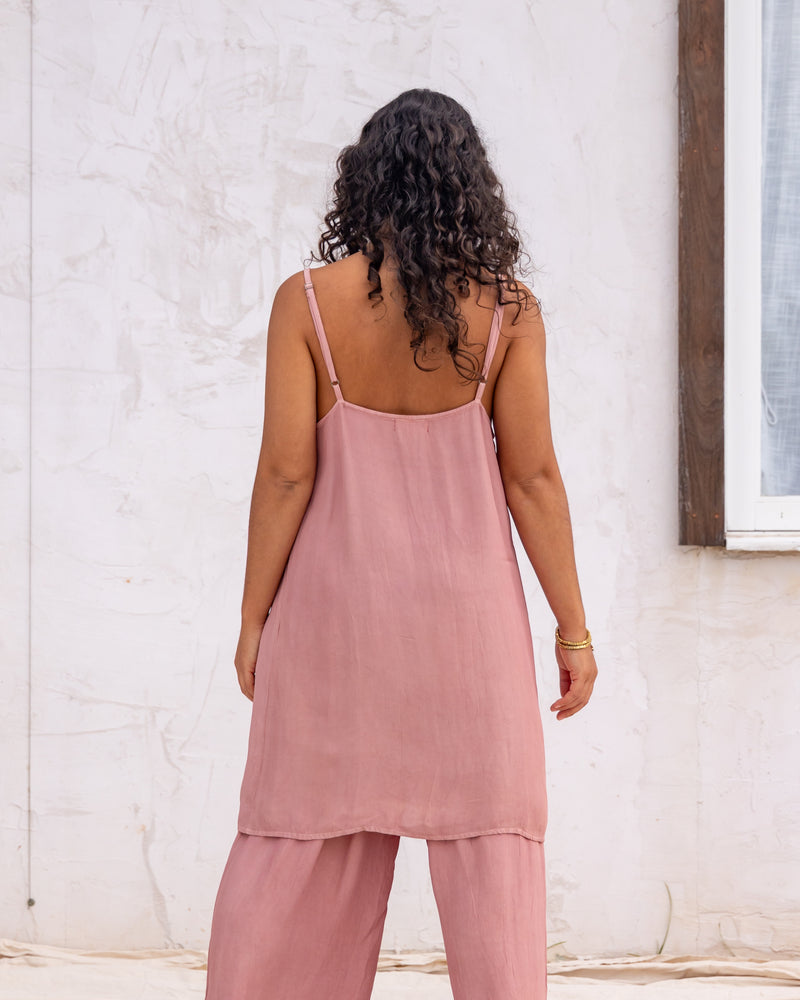
                  
                    woman dressed in miguel straight legged pants and maio mini slip in orange peel fibre in dirty rose pink standing in front of a white wall
                  
                