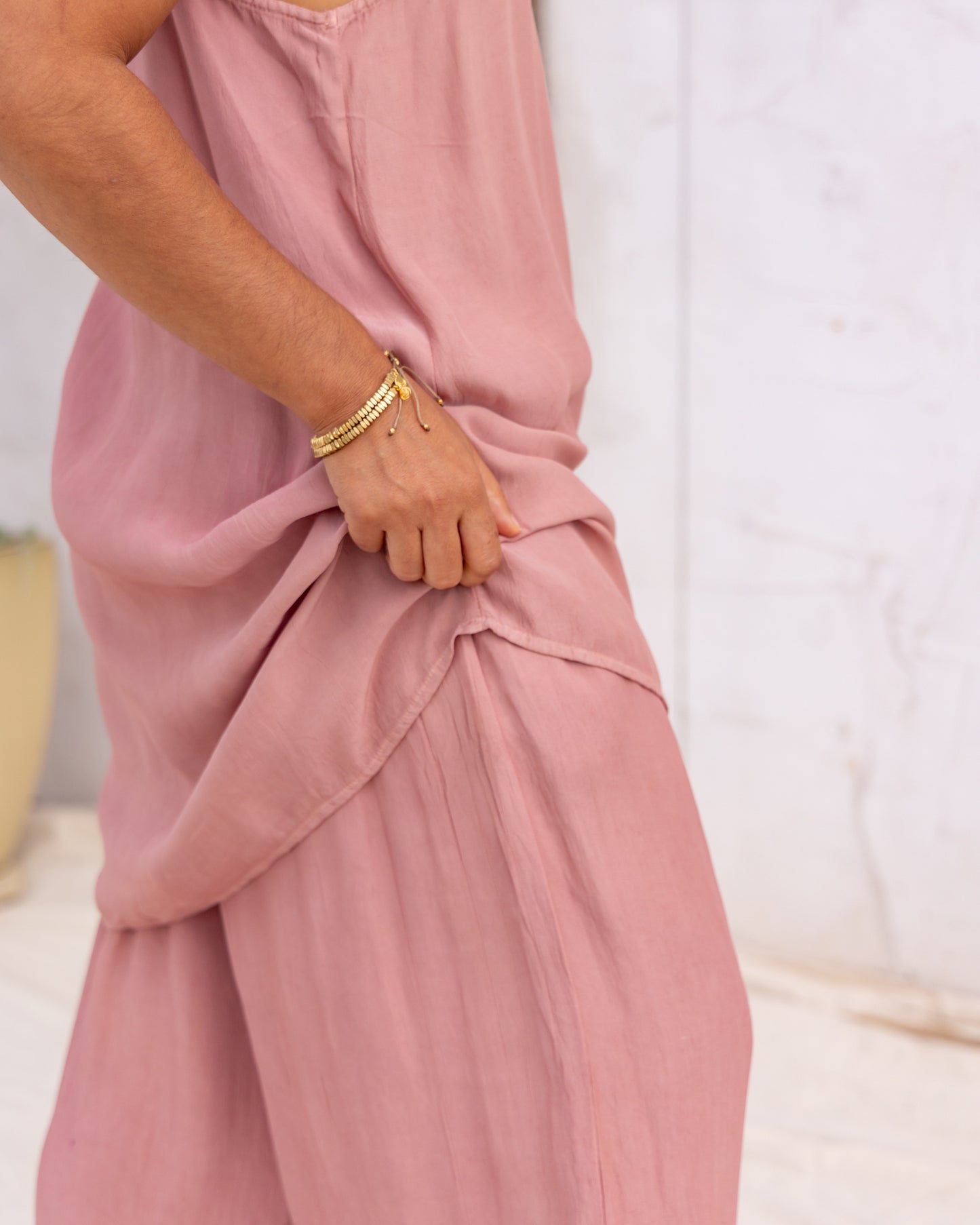 
                  
                    woman dressed in miguel straight legged pants and maio mini slip in orange peel fibre in dirty rose pink standing in front of a white wall
                  
                