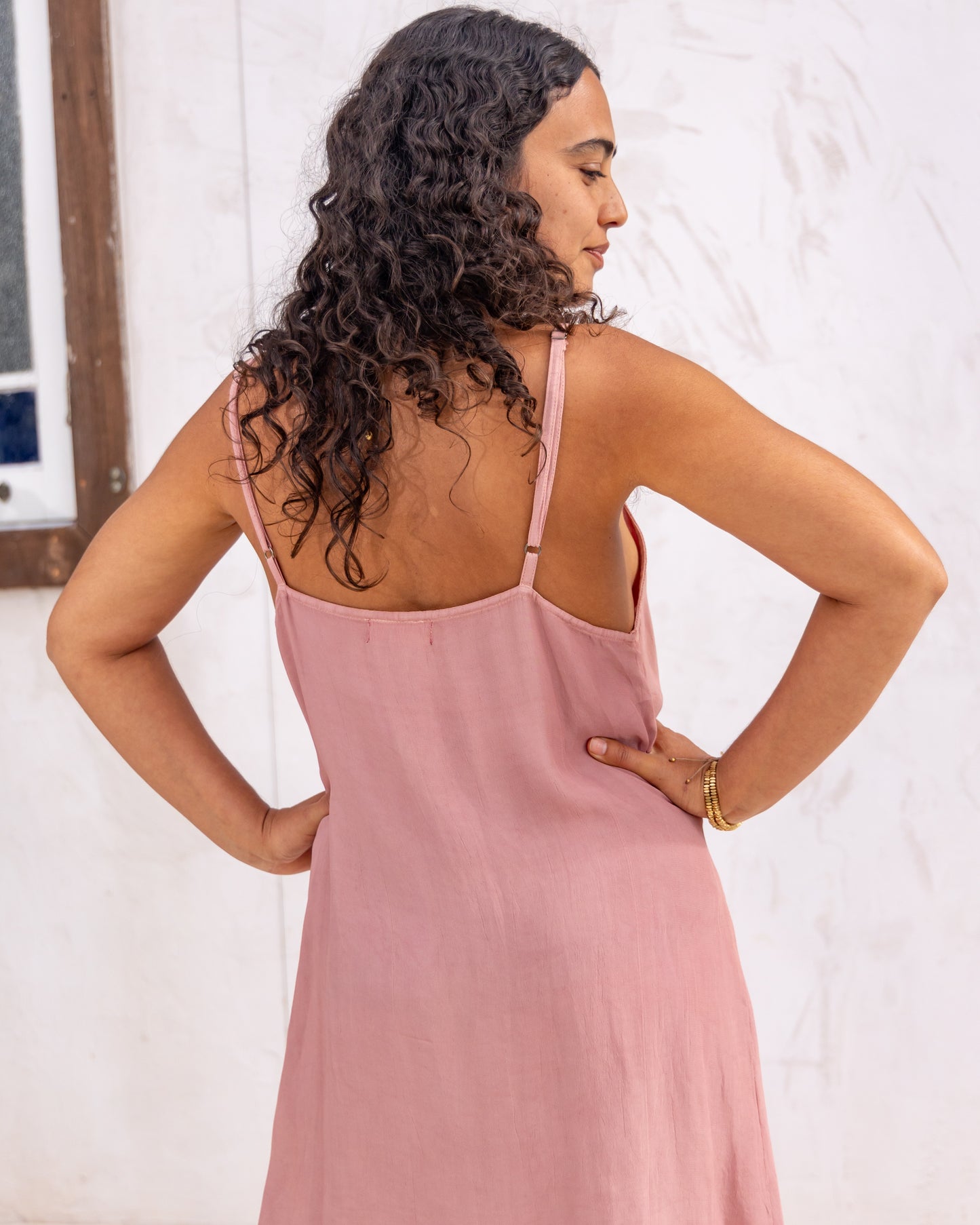 
                  
                    woman dressed in maio mini slip in orange peel fibre in dirty rose pink standing in front of a white wall
                  
                