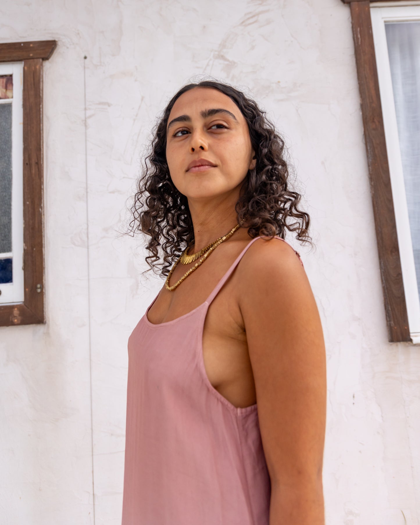 
                  
                    woman dressed in maio mini slip in orange peel fibre in dirty rose pink standing in front of a white wall
                  
                