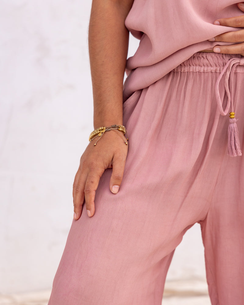 
                  
                    woman dressed in miguel straight legged pants and maio mini slip in orange peel fibre in dirty rose pink standing in front of a white wall
                  
                