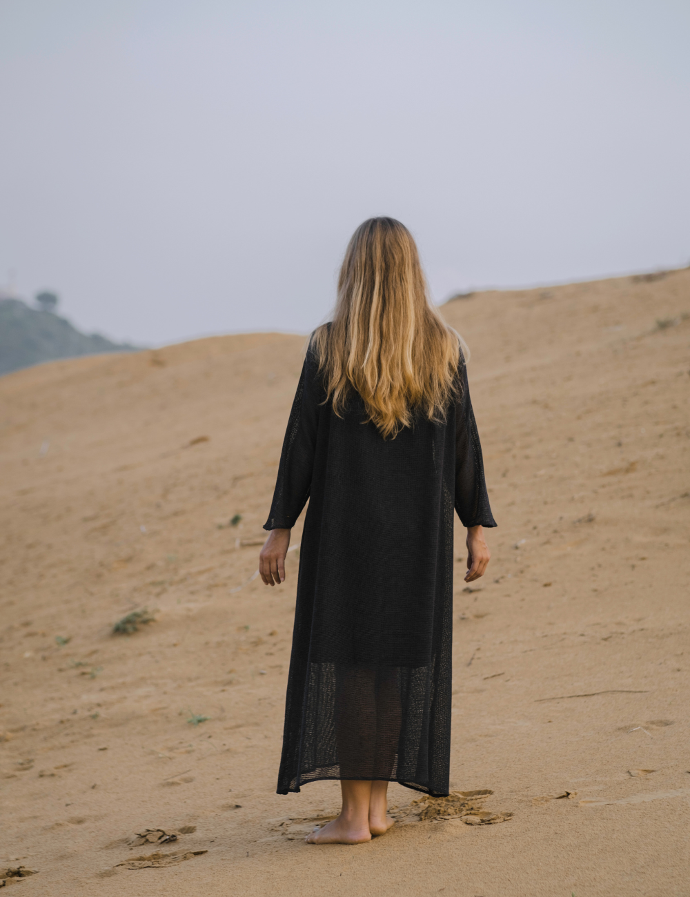 
                  
                    woman from behind dressed in oversized maxi dress in net charcoal in Indian desert
                  
                