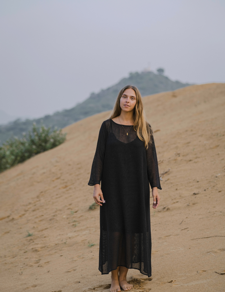 woman dressed in oversized maxi dress in net charcoal in Indian desert with plant in background