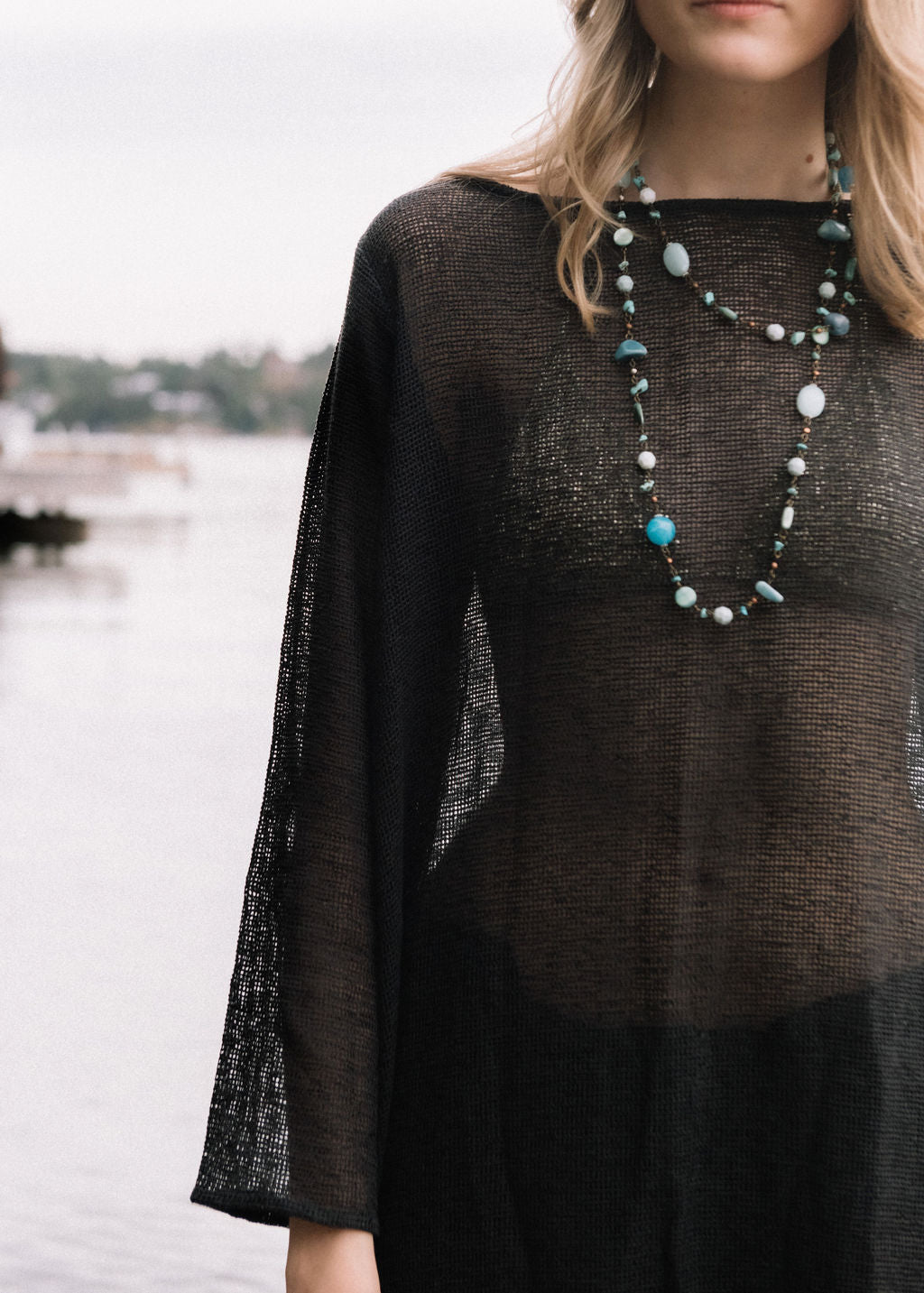 women dressed in netted midi dress in charcoal in front of ocean