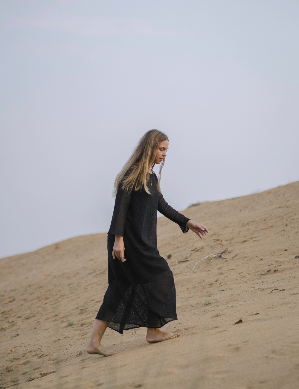 
                  
                    woman dressed in oversized maxi dress in net charcoal walking in Indian desert
                  
                
