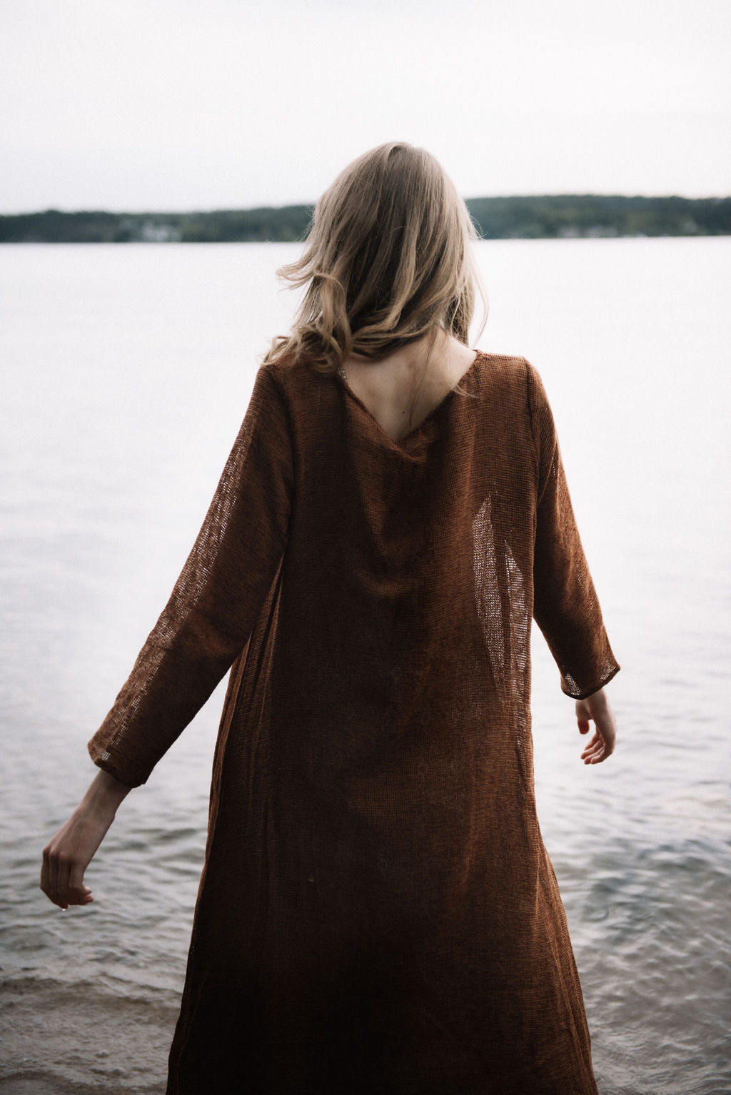 
                  
                    women dressed in netted midi dress in rust in front of ocean
                  
                