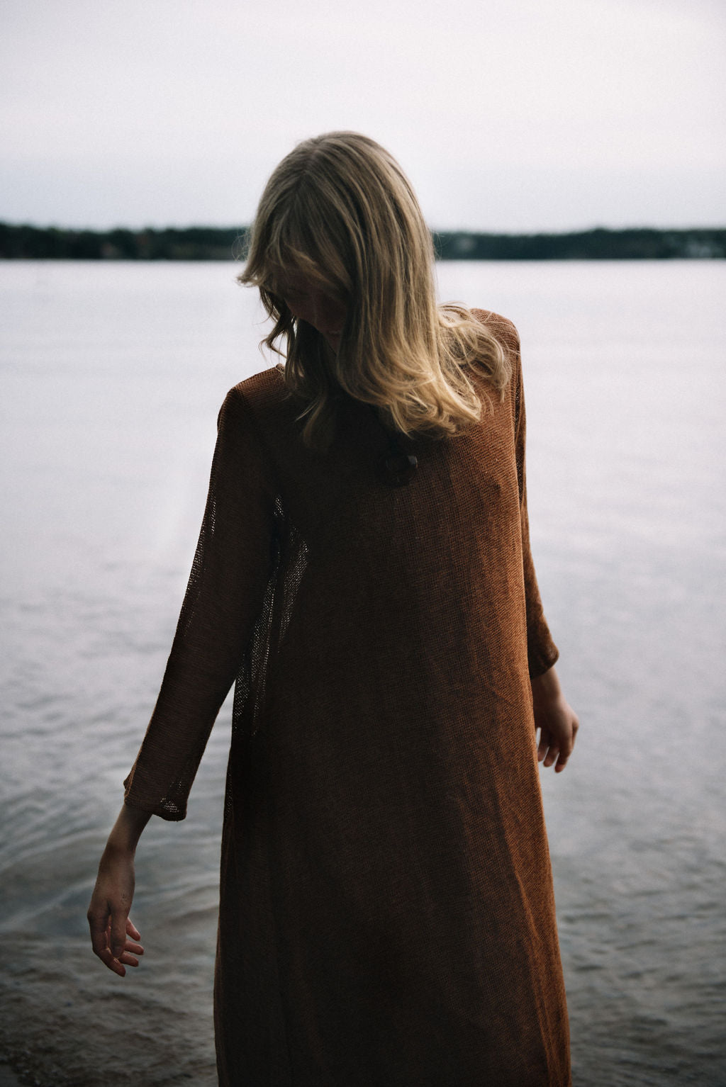 
                  
                    women dressed in netted midi dress in rust in front of ocean
                  
                