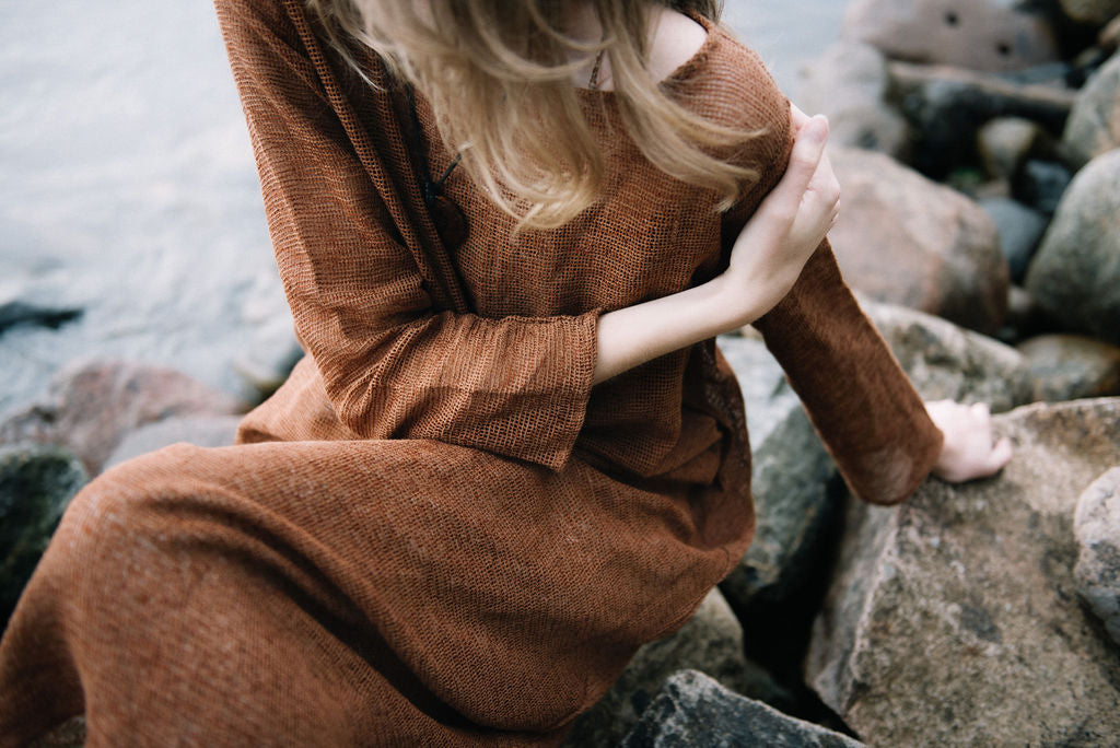 
                  
                    women dressed in netted midi dress in rust in front of ocean
                  
                