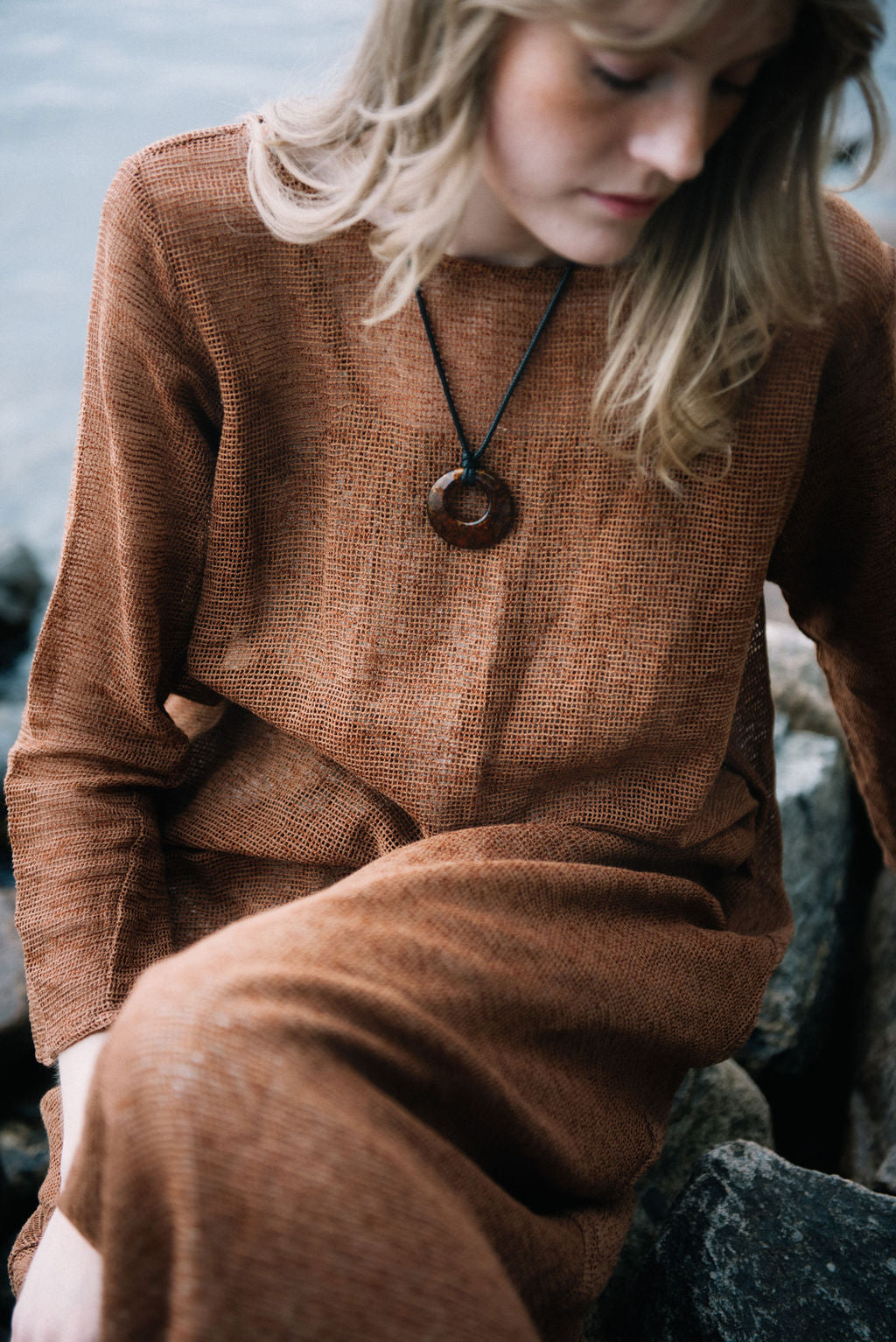 women dressed in netted midi dress in rust in front of ocean