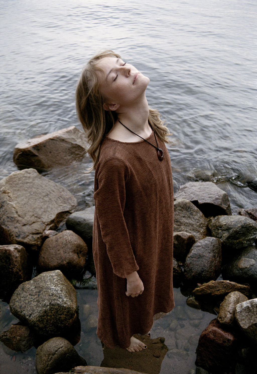 women dressed in netted midi dress in rust in front of ocean