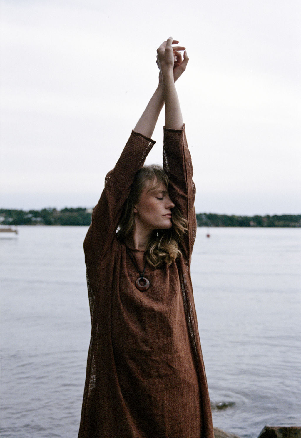 
                  
                    women dressed in netted midi dress in rust in front of ocean
                  
                