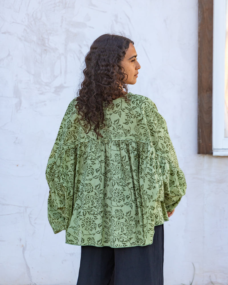 
                  
                    woman dressed in palma billowing sleeves top in gooseberry green print in front of white wall
                  
                