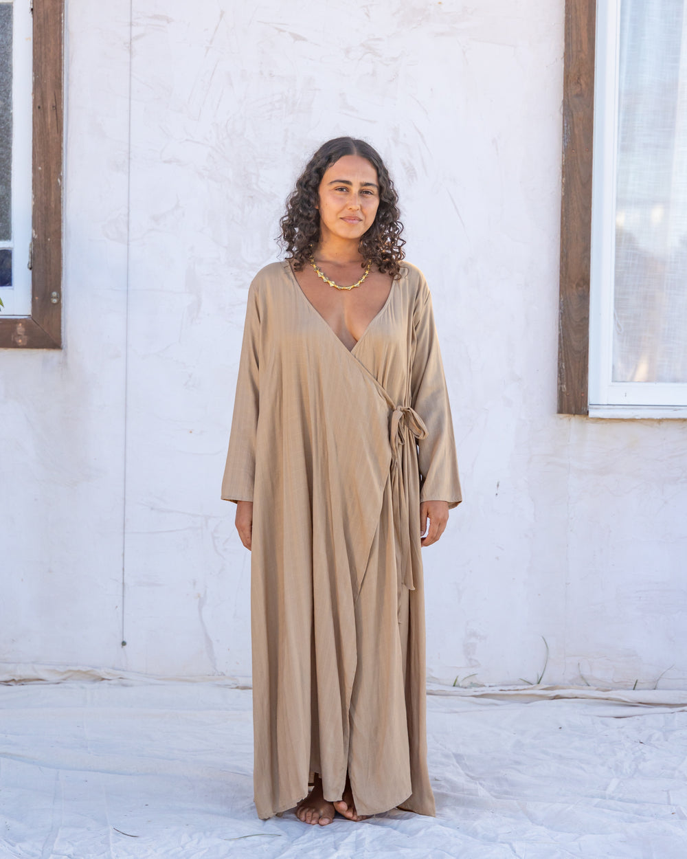 woman dressed in santo organic sugarcane wrap dress standing in front of a white wall