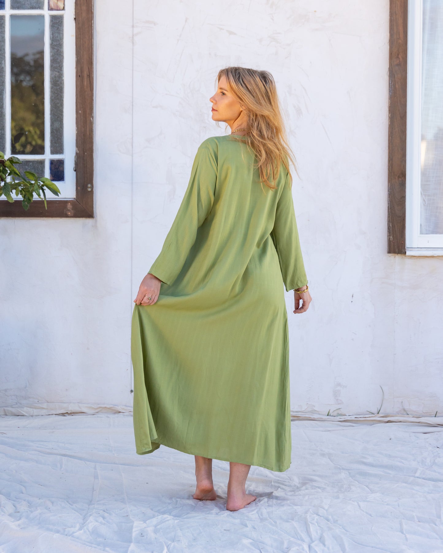 
                  
                    woman dressed in santo organic sugarcane wrap dress in green forest standing in front of a white wall
                  
                