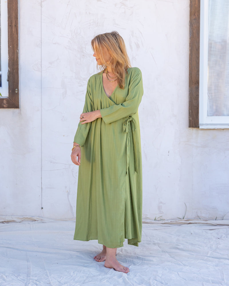 
                  
                    woman dressed in santo organic sugarcane wrap dress in green forest standing in front of a white wall
                  
                