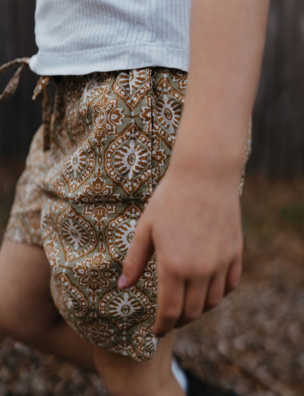young girl wearing indian block printed shorts in retro funk print on lawn