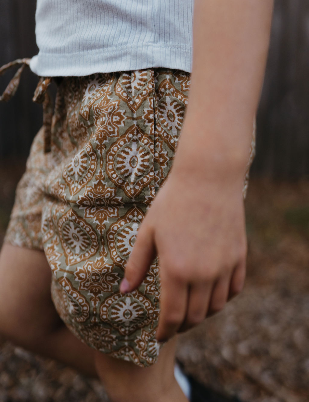 
                  
                    young girl wearing indian block printed shorts in retro funk print on lawn
                  
                