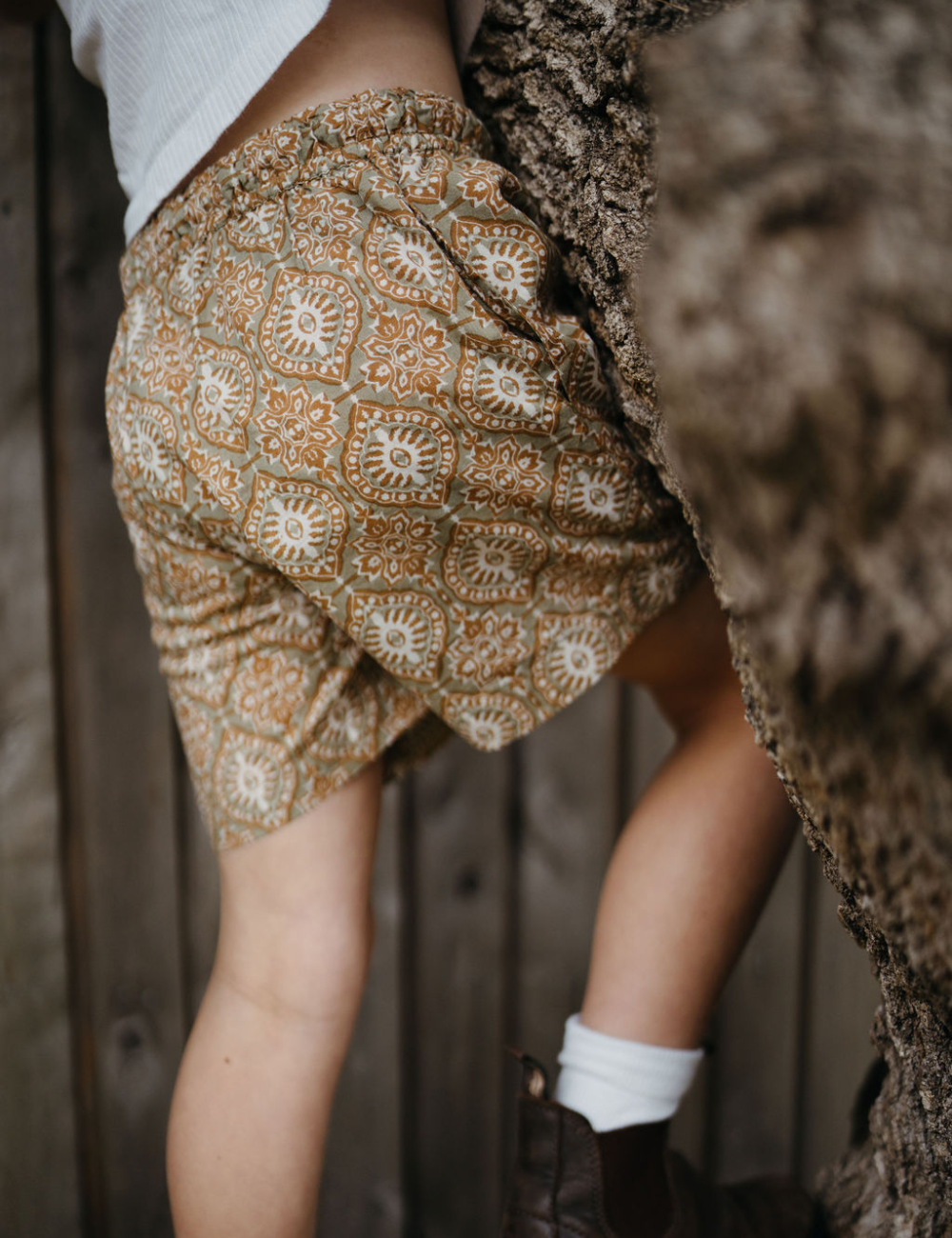 
                  
                    young girl climbing tree wearing Indian block printed shorts in retro funk print
                  
                