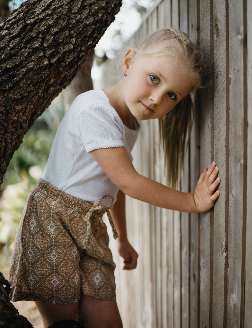 
                  
                    young girl in front of fence wearing Indian block printed shorts in retro funk print
                  
                