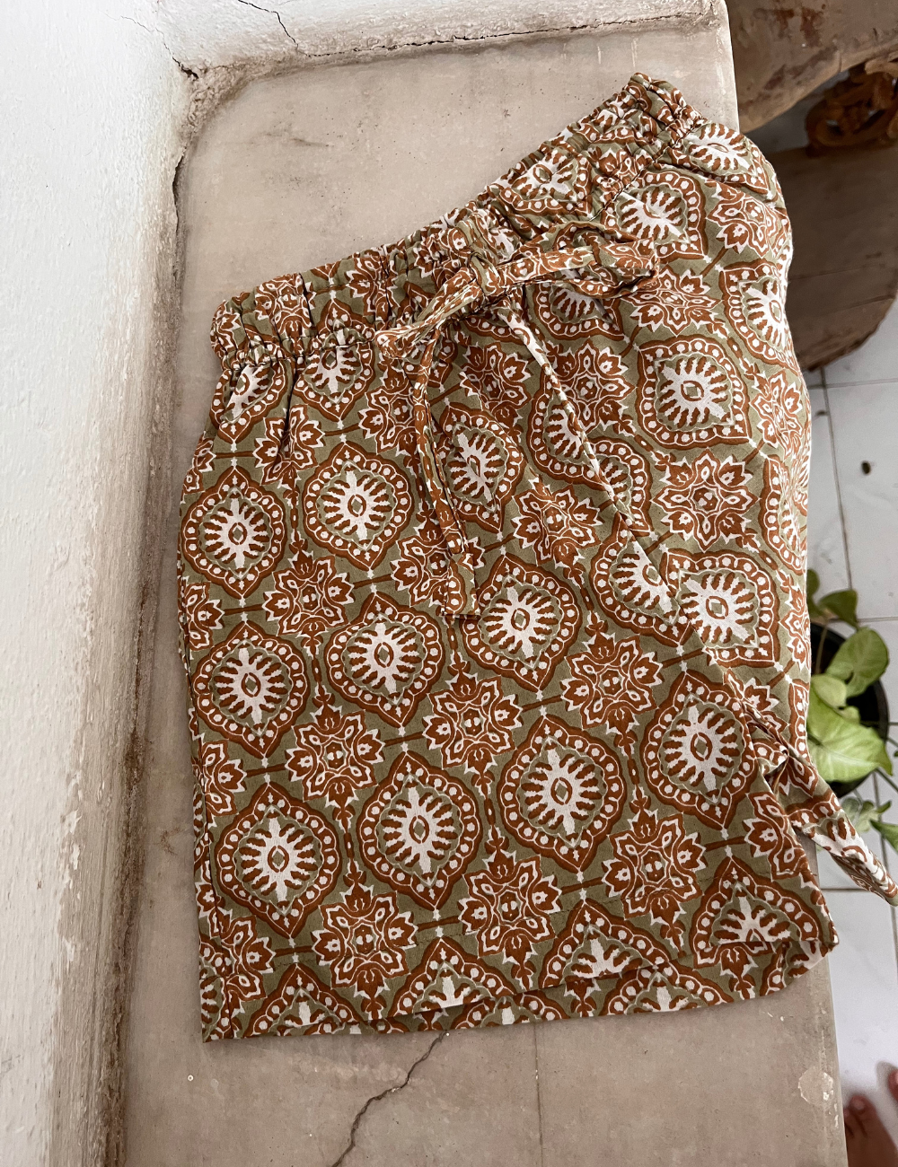 
                  
                    flat lay photo of indian block printed shorts in retro funk print on concretre shelf
                  
                