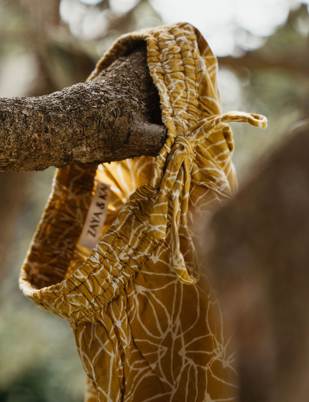 
                  
                    Indian retro block printed pants in mustard seed print hanging on tree branch
                  
                