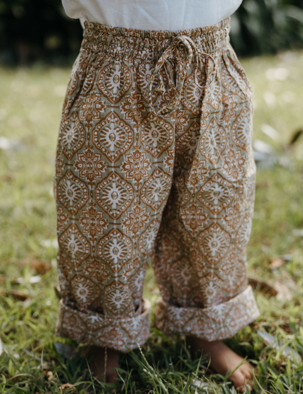 
                  
                    young girl wearing indian block printed pants in retro funk print on lawn
                  
                