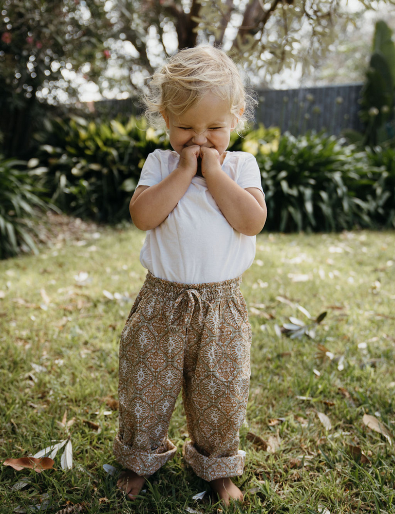 young girl giggling wearing white singlet indian block printed shorts in retro funk print on lawn